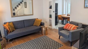 A living room with a grey sofa, a patterned rug, a coffee table, and a television. - Central Cute Garden Cottage Close to Town & Beach (Brighton and Hove)
