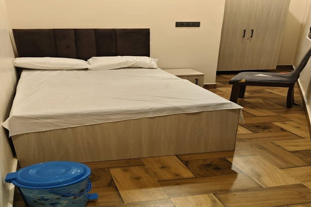 Une chambre à coucher avec un lit, une chaise, une petite table et un récipient bleu.