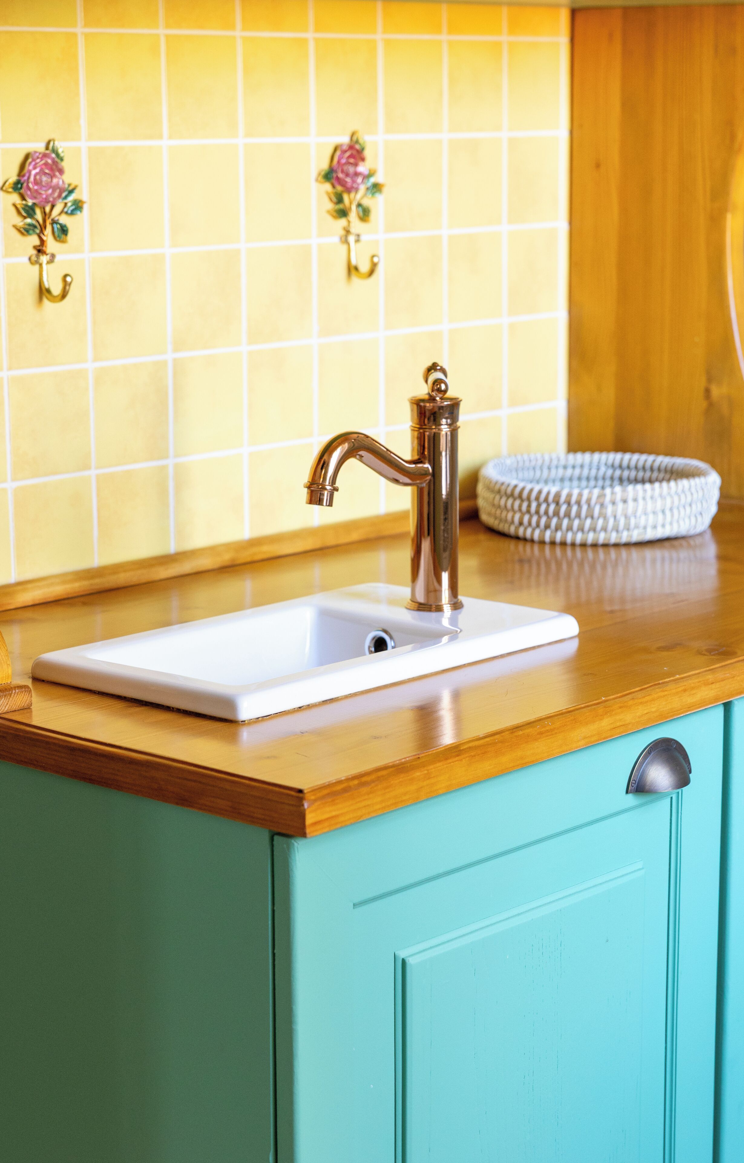 A kitchen with a white sink, a wooden countertop, and a turquoise cabinet.