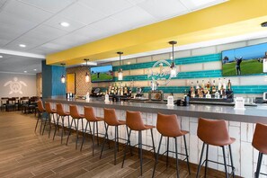 Eine Bar mit einer Theke, Barhocker und einem Fernseher, der Golf zeigt.