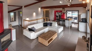 Ein modernes Wohnzimmer mit einer Eckcouch, einem Holztisch und einer Küchenzeile mit Bar.