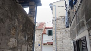 Une rue étroite bordée d’immeubles en pierre, avec un numéro 19 bien visible et un tas de matériaux de construction.