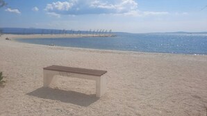 Une plage avec un banc, un ciel dégagé et une mer calme.