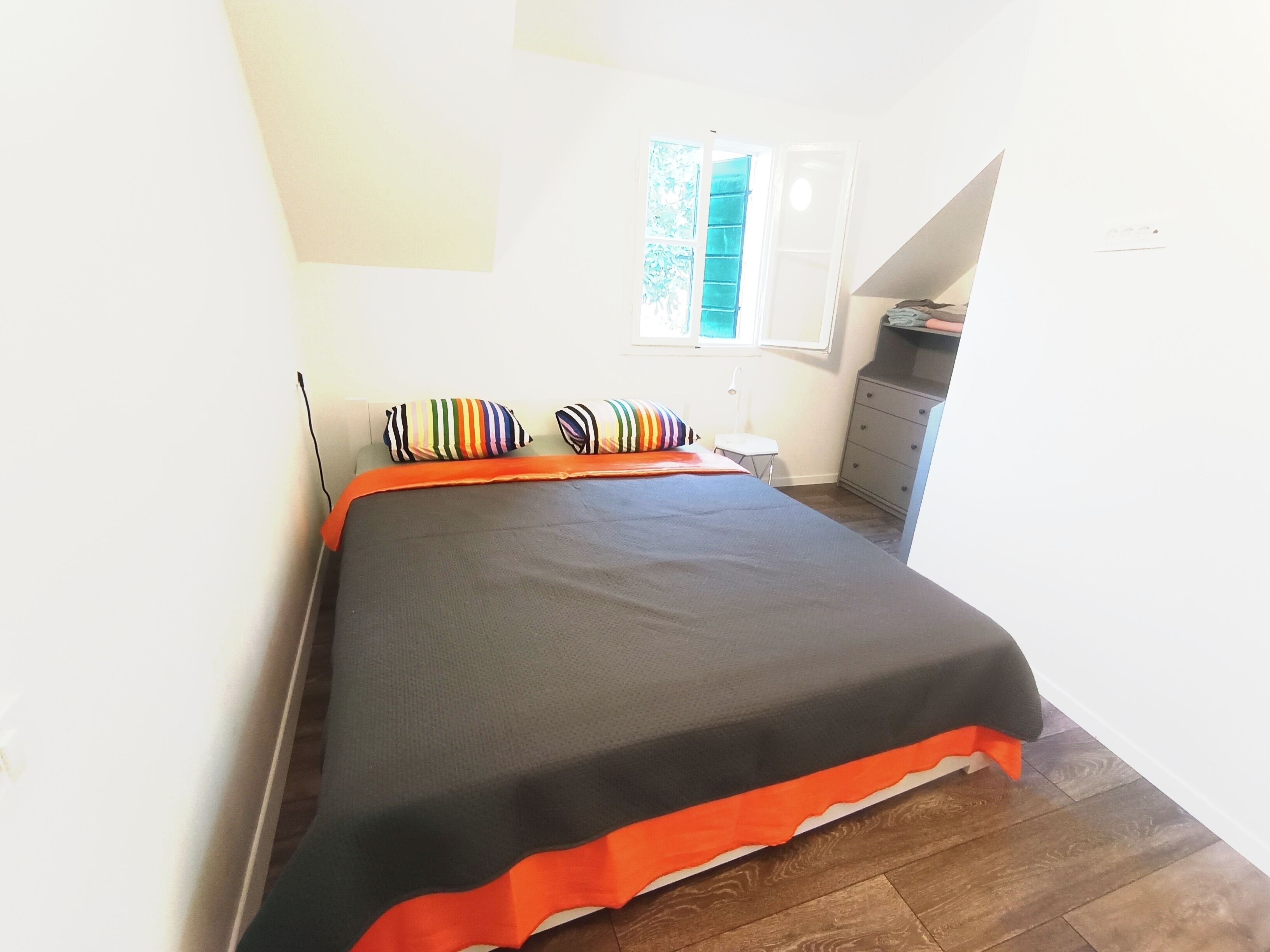 A bedroom with a bed, a window, a desk, and a chair.
