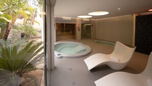 A modern indoor pool area with a hot tub, two white lounge chairs, and a glass door leading to a staircase. - Villa Isidor with private pool - My Rental Homes (San Jose)