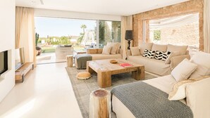 A modern living room with a large window, a sofa set, a coffee table, and a TV. - Villa Isidor with private pool - My Rental Homes (San Jose)