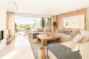 A modern living room with a large window, a sofa set, a coffee table, and a TV. - Villa Isidor with private pool - My Rental Homes (San Jose)