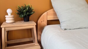 A bedroom with a wooden bed, a bedside table with a potted plant, and a white pillow. - Family home for 8–10 people • Garden • North Coast of Finistère (Plouzévédé)