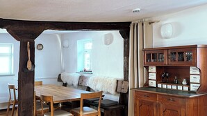 Un coin repas rustique avec une table et des chaises en bois, un meuble avec des compartiments étiquetés et un pilier en pierre.
