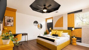 A modern bedroom with a bed, desk, and potted plant.