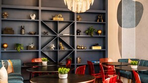 A modern interior with a dark blue wall, geometric shelving, and red chairs.