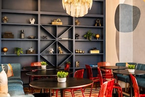 Un interior moderno con una pared azul oscuro, estanterías geométricas y sillas rojas.