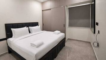 Una habitación de hotel moderna con una cama grande, un televisor de pantalla plana en la pared y un armario con espejo.