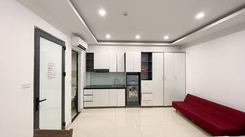 Un espacio habitable compacto con kitchenette, comedor y sofá rojo.
