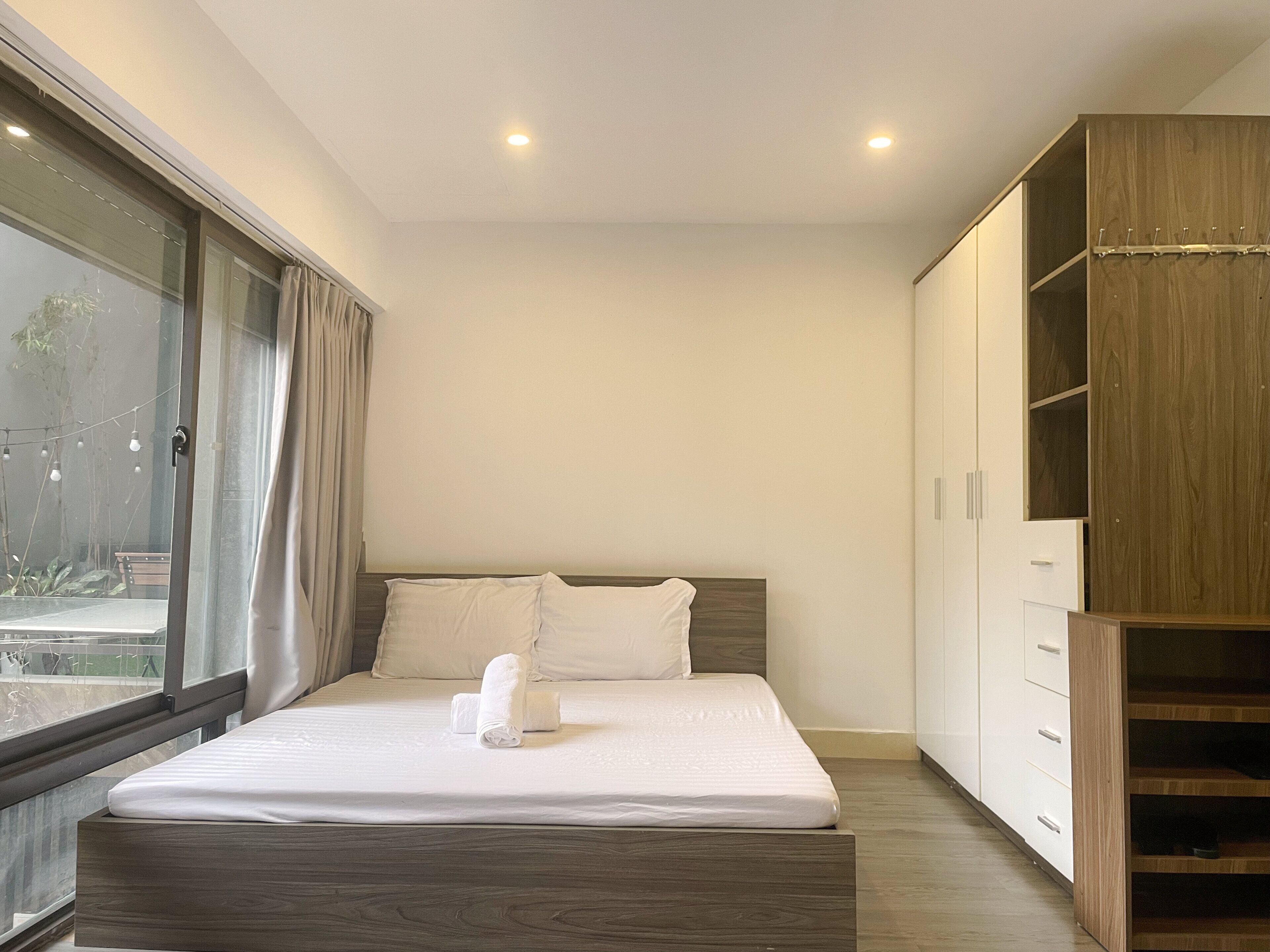 Un dormitorio moderno con una cama grande, un armario de madera y vistas por una ventana.