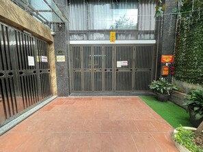 A gated entrance with a tiled patio, a green artificial turf area, and potted plants. - Biko Apartment (Hanoi)