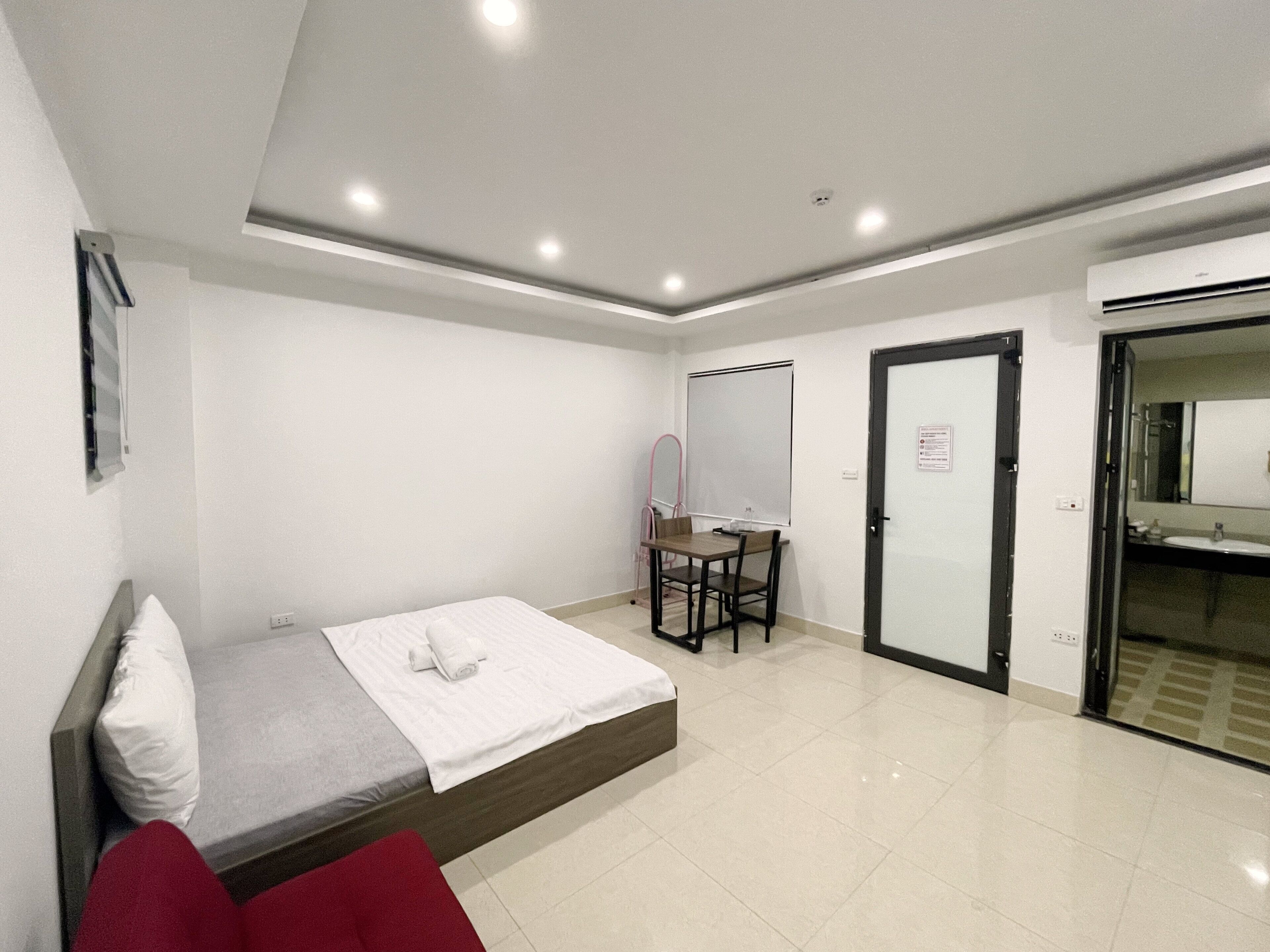 Ein Hotelzimmer mit einem Bett, einem Schreibtisch mit Stuhl, einem Spiegel und einem Badezimmer mit Waschbecken und Spiegel.