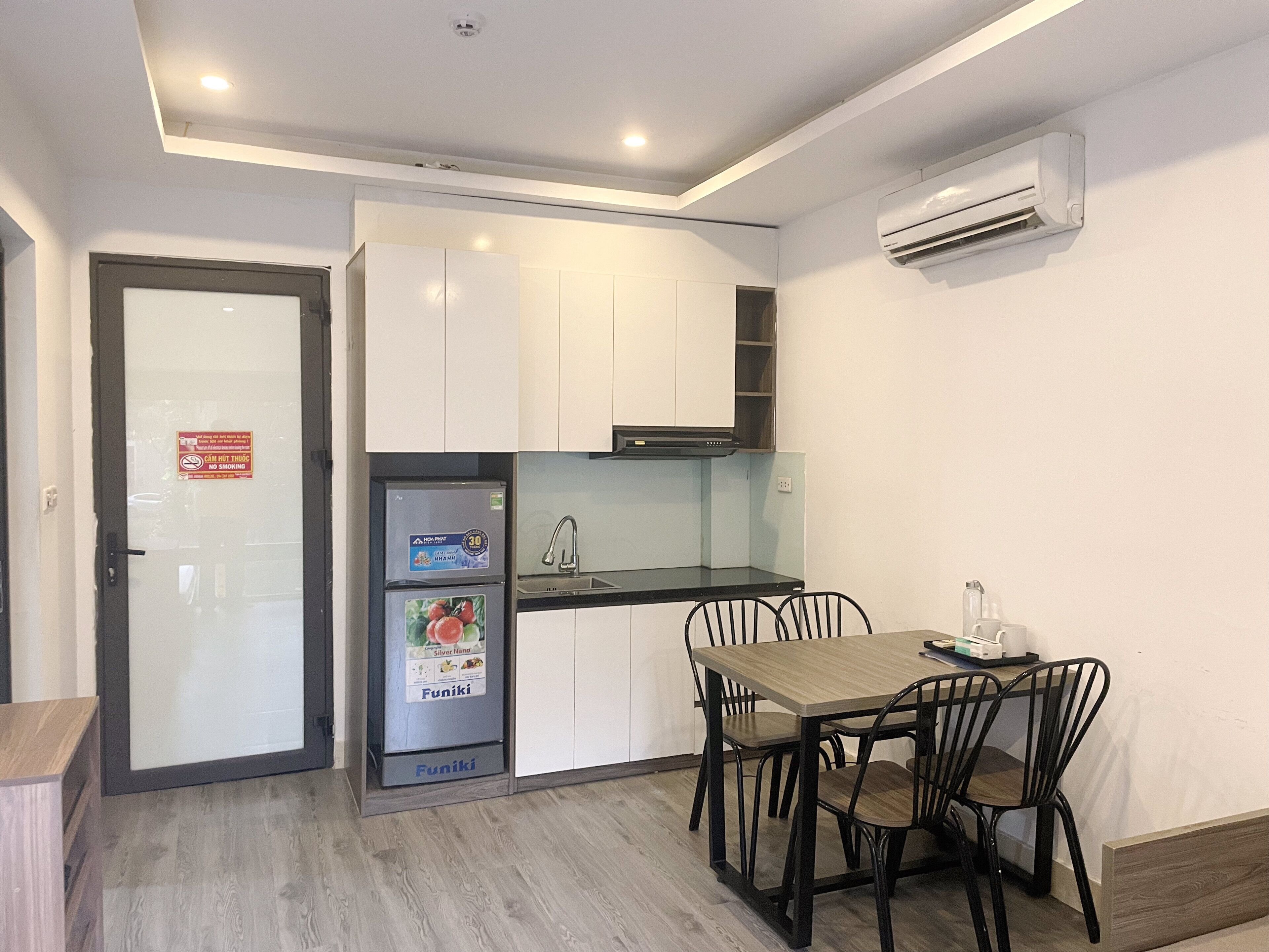 Cocina compacta con gabinetes blancos, estufa integrada y comedor con mesa y sillas.