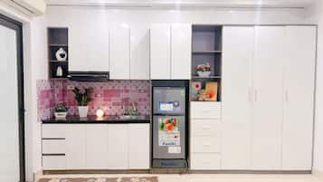 Una cocina moderna con armarios blancos, encimera negra y refrigerador integrado.