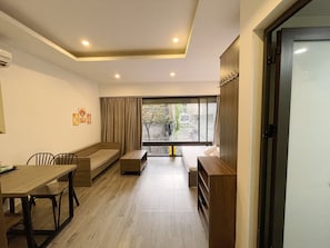 A modern interior with a dining area, seating, and a view through a large window. - Biko Apartment (Hanoi)