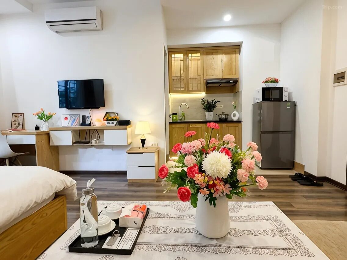 Une chambre d’hôtel de taille réduite, équipée d’un lit, d’un bureau, d’une télévision, d’une kitchenette et d’un réfrigérateur.