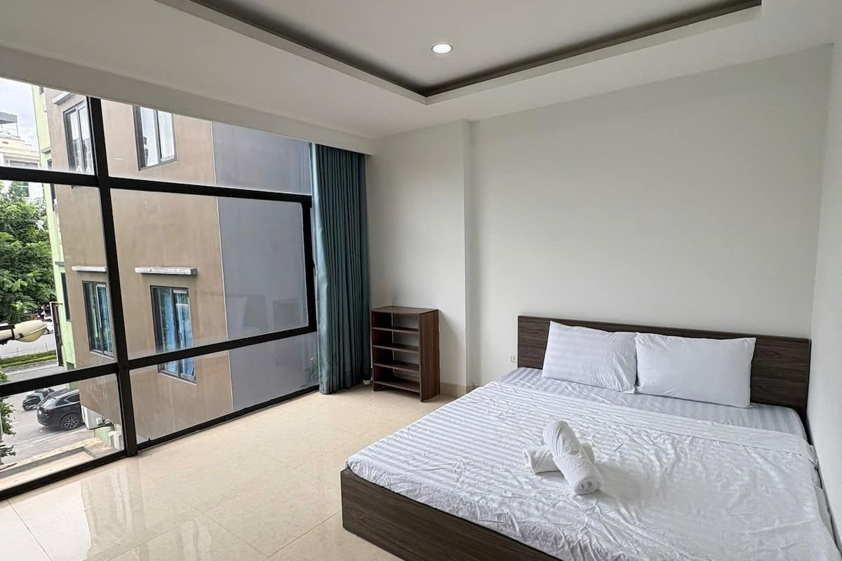 A modern hotel room with a large bed, a view of the city, and a balcony.