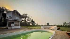 A two-story house with a balcony, a swimming pool, and a garden. - PILIBHIT Forest & Feast (Puranpur)