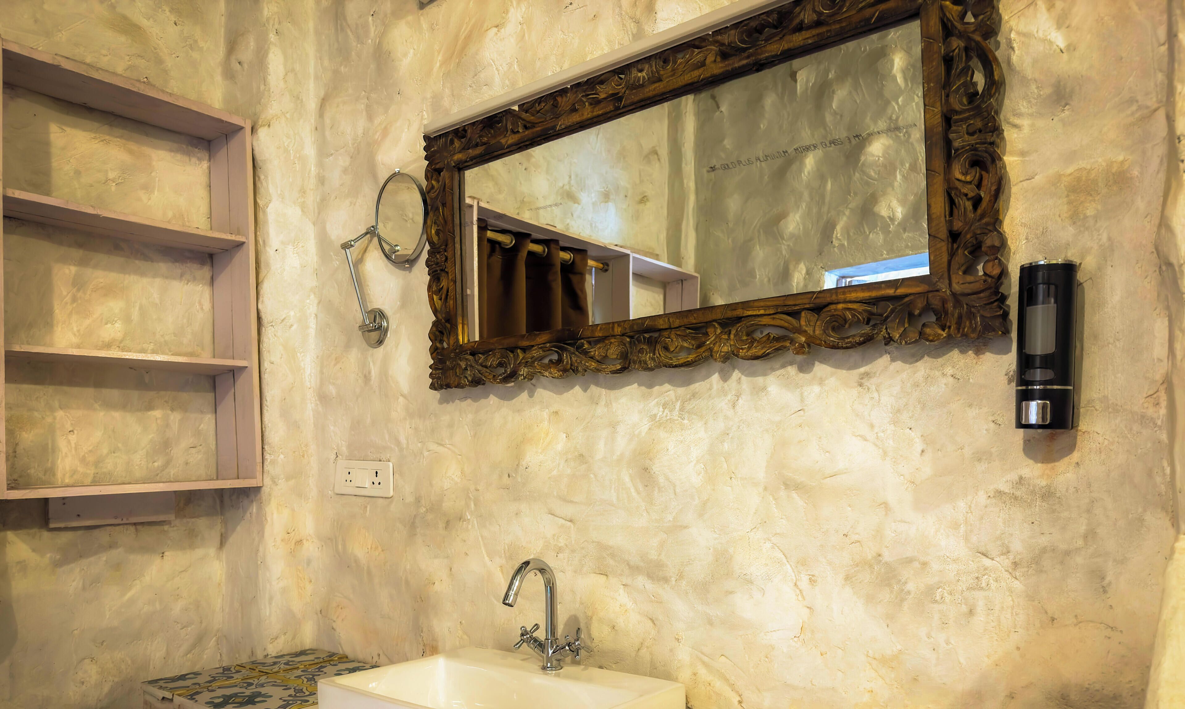 A bathroom with a large ornate mirror, a sink, and a towel rack.