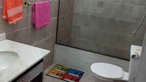 Un baño con ducha, inodoro, lavamanos y un cubo de basura.
