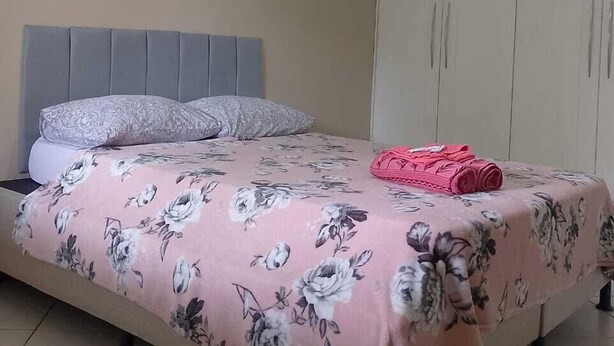 Un dormitorio con cama, armario y ventilador de techo.