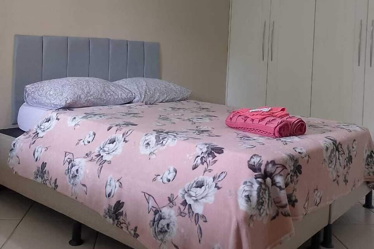 A bedroom with a bed, a wardrobe, and a ceiling fan.