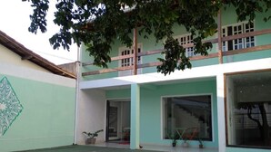 Un edificio con fachada verde y blanca, un balcón y una escalera que conduce a un piso superior.