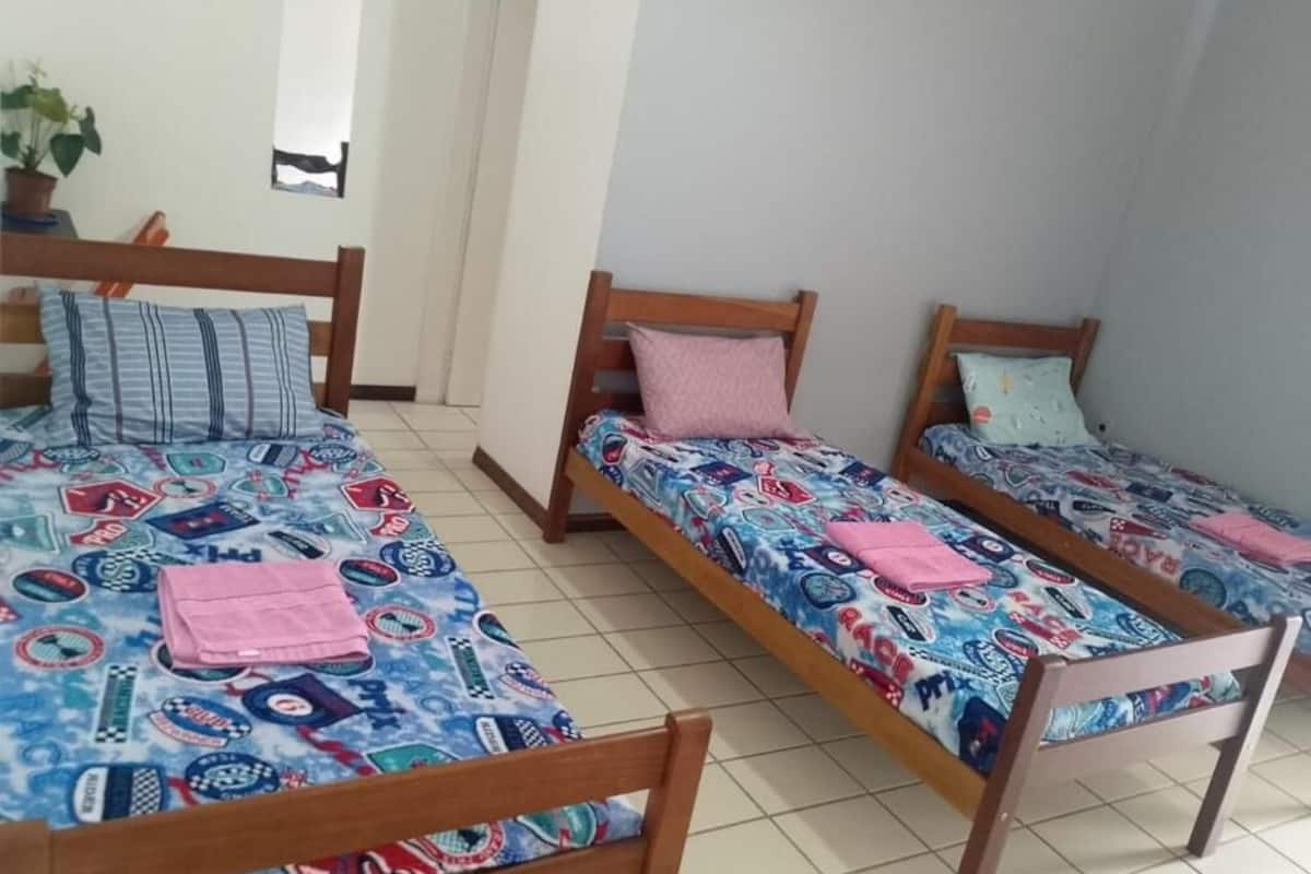 A room with three wooden beds, each with a patterned bedspread and pillows.