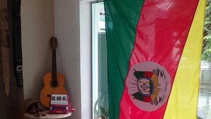 Una habitación con una bandera, una guitarra, una silla y una mesa.