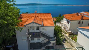 Un bâtiment situé sur la côte, avec un toit recouvert de tuiles rouges, un escalier et une vue sur la mer.