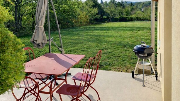 Un patio con tavolo e sedie, un barbecue e una sedia a dondolo.