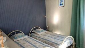 Una stanza con due letti, una scrivania, una lampada e un quadro appeso al muro.