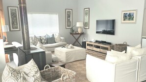 A living room with a fireplace, white sofas, a television, and artwork on the walls.