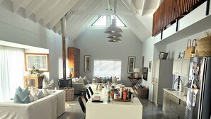 A spacious living area with a high ceiling, a central island, and a kitchen with modern appliances.