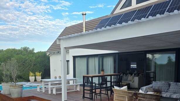 A modern house with a deck, outdoor furniture, and a swimming pool.