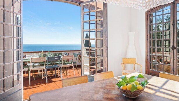 An open terrace with a view of the sea, a dining table with chairs, and a decorative ceiling light. - Maison Soleillade – A rustic, peaceful home with a view of the sea (Roquebrune-Cap-Martin)