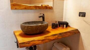 A bathroom with a stone sink, wooden vanity, and a towel rack.