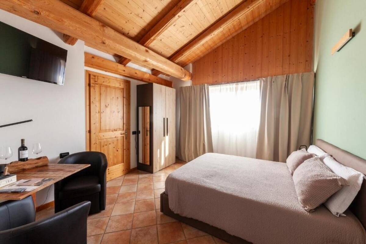 Una camera da letto con un letto, una scrivania con sedie, una televisione e un soffitto in legno.