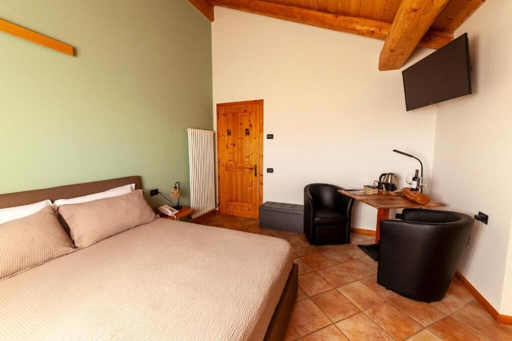 Ein Schlafzimmer mit einem Bett, einem Schreibtisch mit Stuhl, einem Fernseher und einer Heizung.