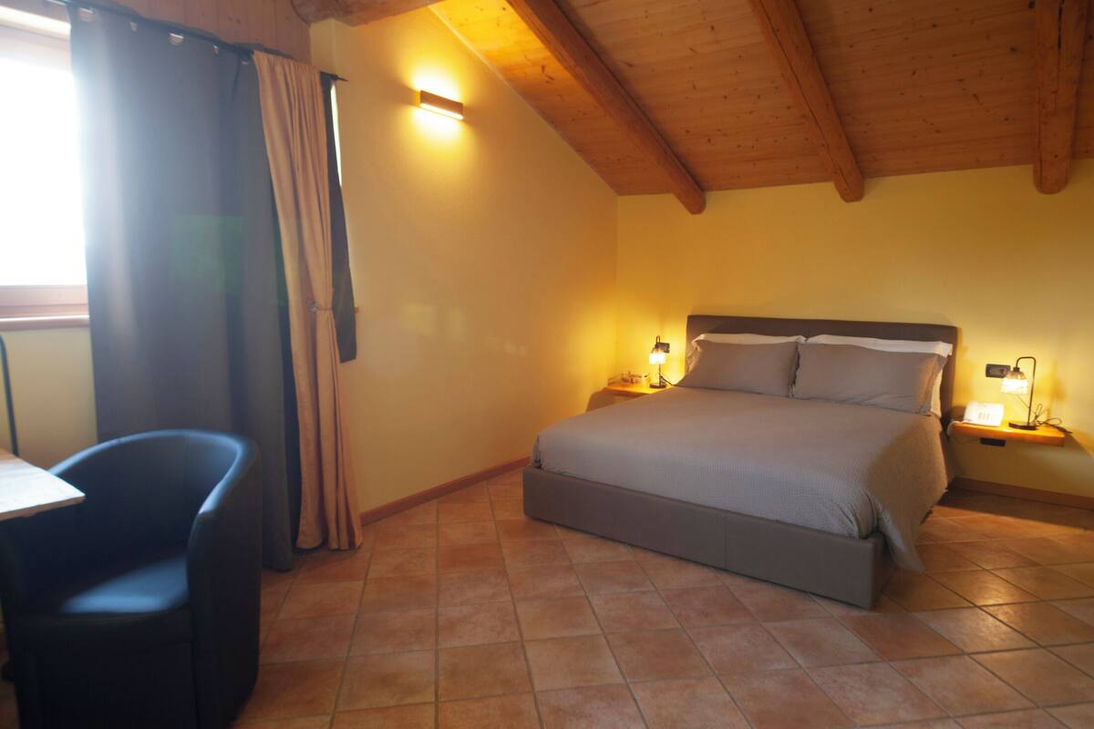 Una camera da letto con un letto, abat-jour, una sedia e una finestra con tende.