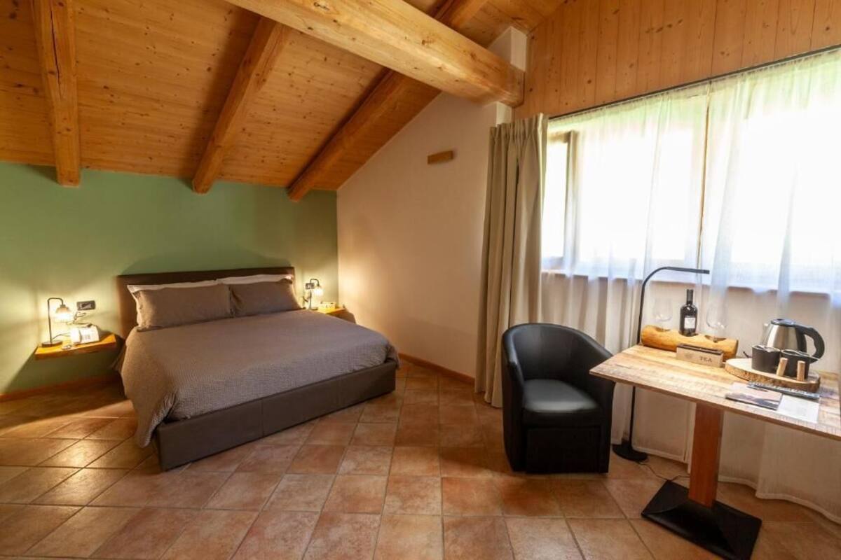 Una camera da letto con un letto, una scrivania, una sedia, un comodino e una finestra con tende.