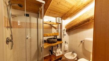 A bathroom with a glass shower enclosure, wooden shelves, a sink, and a toilet.