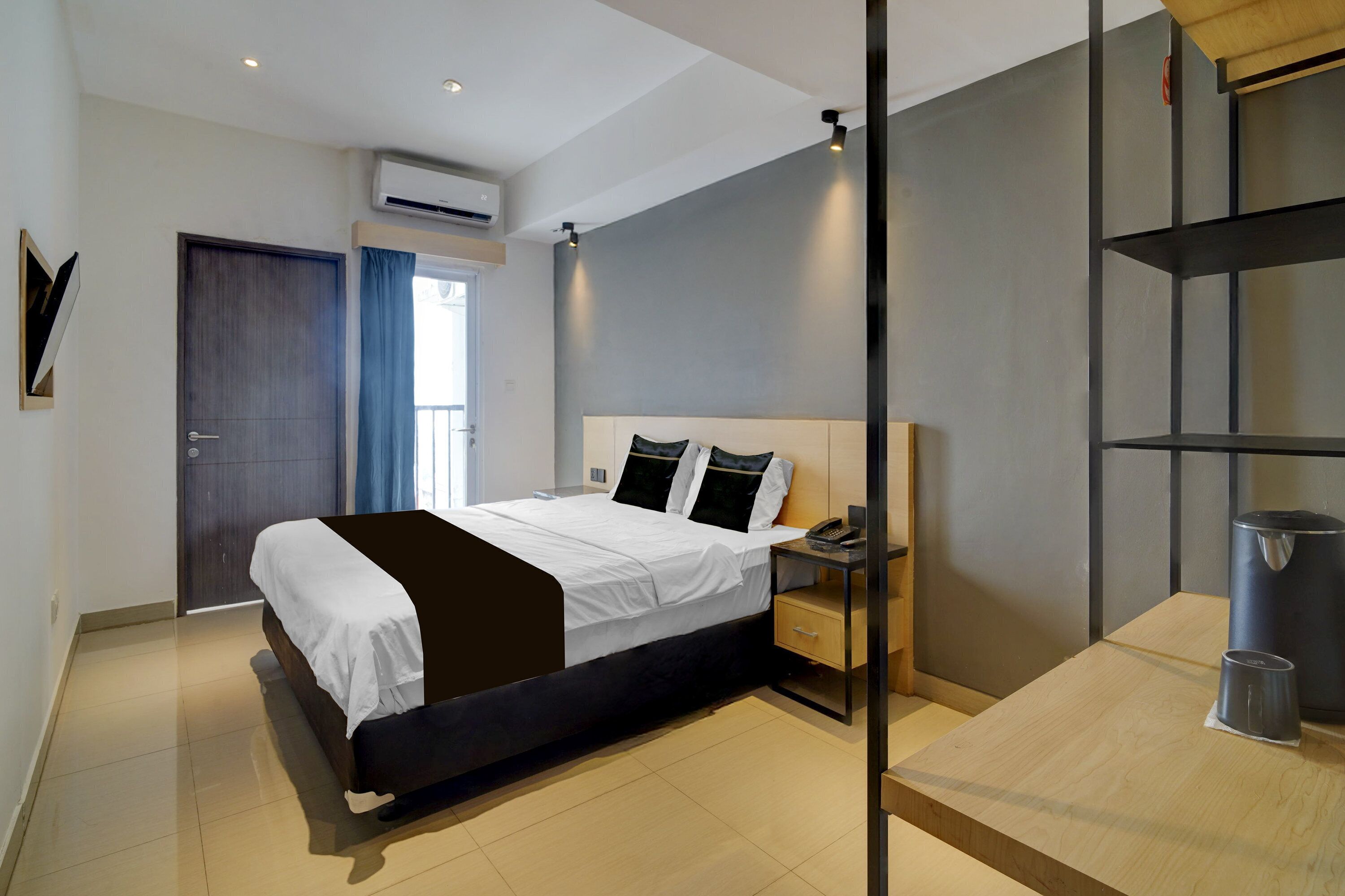 Een moderne hotelkamer met een bed, nachtkastje en een klein bureau.