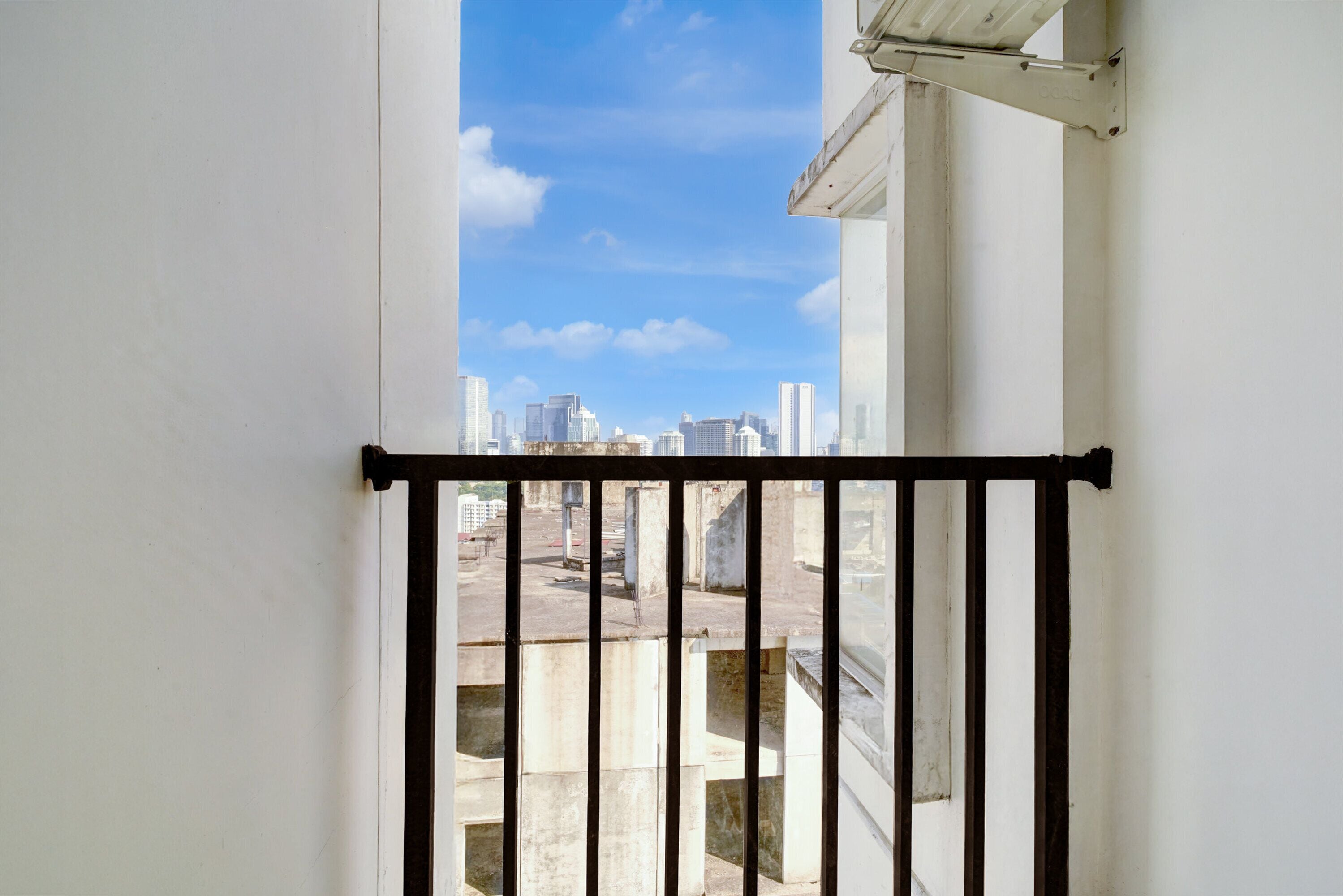 Un balcón con vistas a un paisaje urbano tras una barandilla metálica.