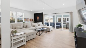 Een moderne woonkamer met een hoekbank, een salontafel en een schuifpui naar een terras.
